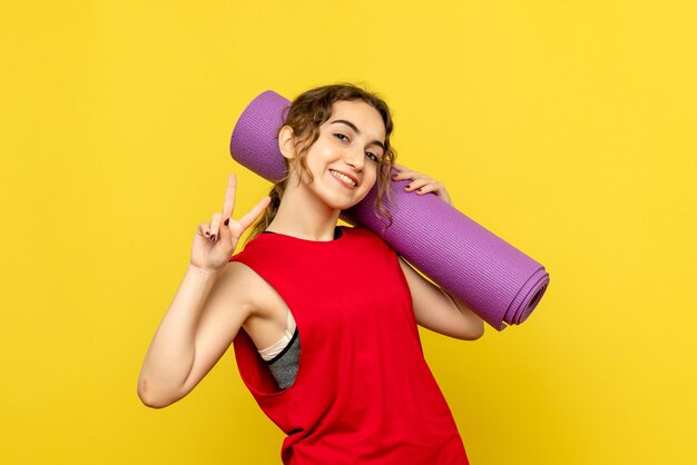 Vista frontale della giovane donna con tappeto viola sulla parete gialla