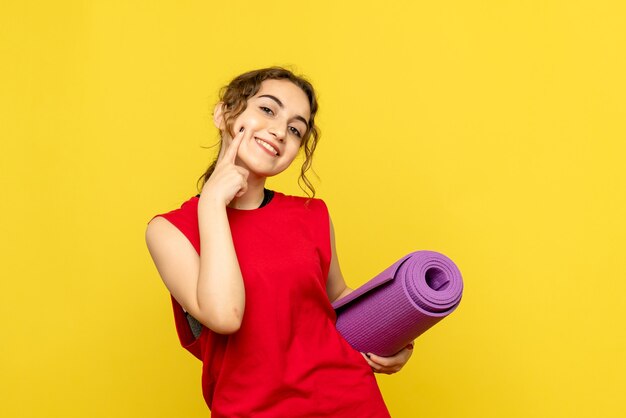 Vista frontale della giovane donna con tappeto viola sulla parete gialla