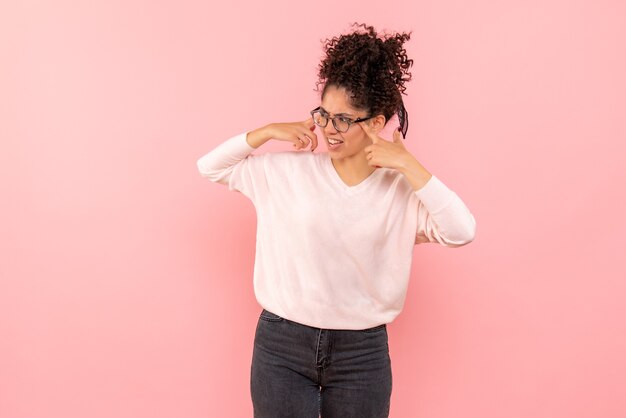 Vista frontale della giovane donna confusa sulla parete rosa