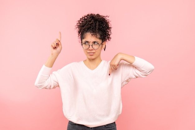 Vista frontale della giovane donna confusa sulla parete rosa