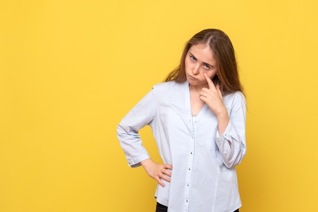 Vista frontale della giovane donna contro il muro giallo