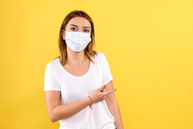 Vista frontale della giovane donna in maschera sterile sulla parete gialla