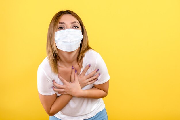 Vista frontale della giovane donna in maschera sulla parete gialla