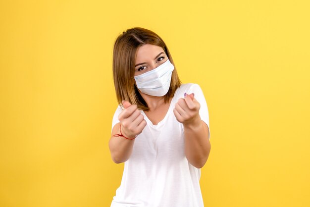 Vista frontale della giovane donna in maschera sulla parete gialla