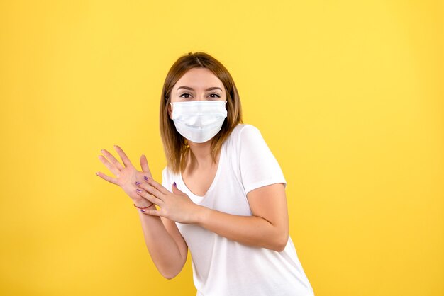 Vista frontale della giovane donna in maschera sulla parete gialla