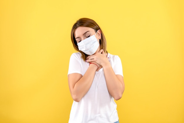 Vista frontale della giovane donna in maschera sulla parete gialla