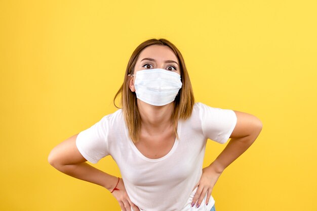 Vista frontale della giovane donna in maschera sulla parete gialla