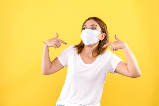 Vista frontale della giovane donna in maschera sulla parete gialla