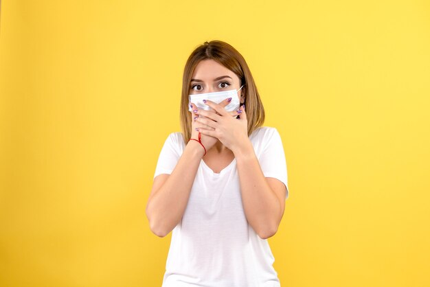 Vista frontale della giovane donna in maschera sulla parete gialla