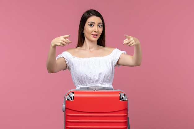 Vista frontale della giovane donna in piedi e si prepara per la vacanza su sfondo rosa viaggio mare viaggio donna all'estero vacanza all'estero