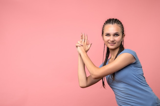 Vista frontale della giovane donna in pistola tenendo la posa in rosa