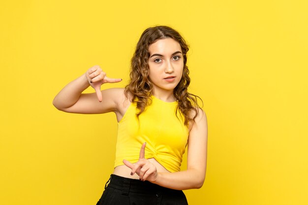 Vista frontale della giovane donna in posa sulla parete gialla