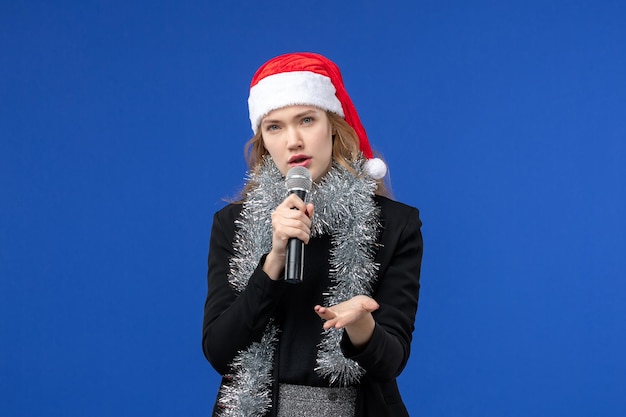 Vista frontale della giovane donna nella festa di karaoke di Capodanno sulla parete blu