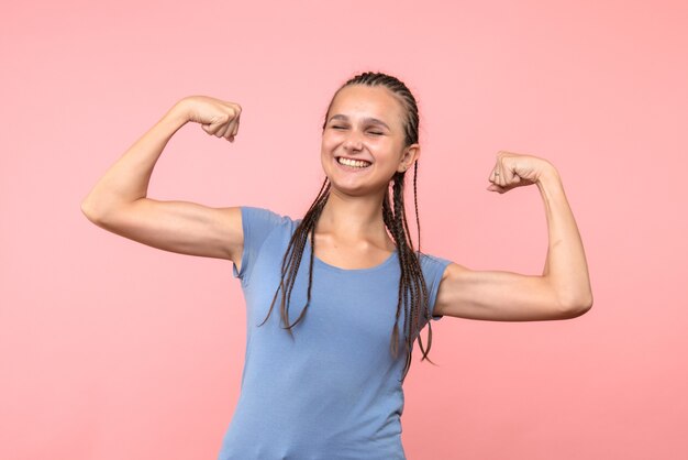 Vista frontale della giovane donna sorridente e flettente sul rosa