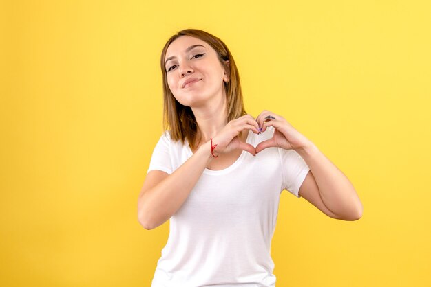 Vista frontale della giovane donna sorridente e invio di amore sulla parete gialla