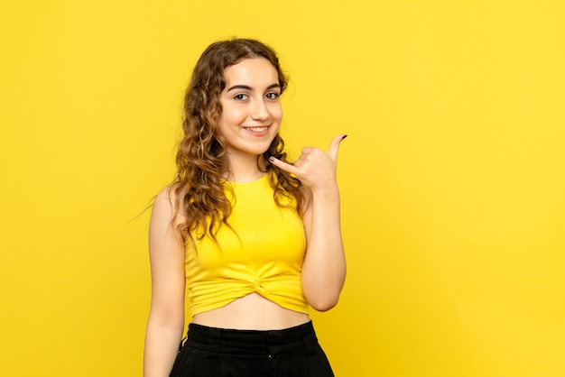 Vista frontale della giovane donna sorridente su una parete gialla