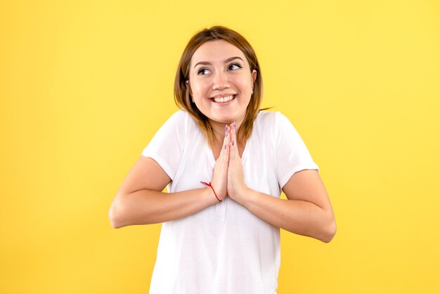 Vista frontale della giovane donna sorridente sulla parete gialla