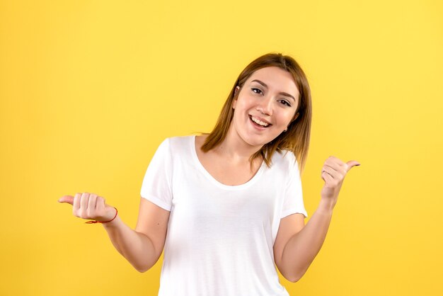 Vista frontale della giovane donna sorridente sulla parete gialla