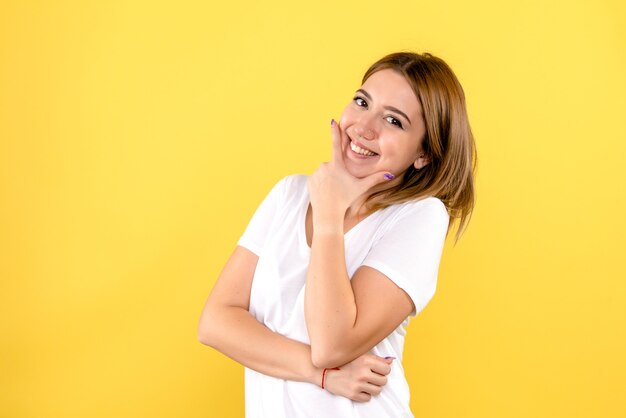 Vista frontale della giovane donna sorridente sulla parete gialla