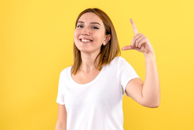 Vista frontale della giovane donna sorridente sulla parete gialla
