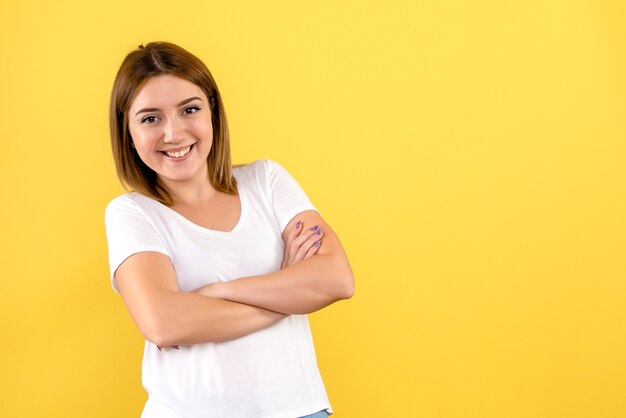 Vista frontale della giovane donna sorridente sulla parete gialla