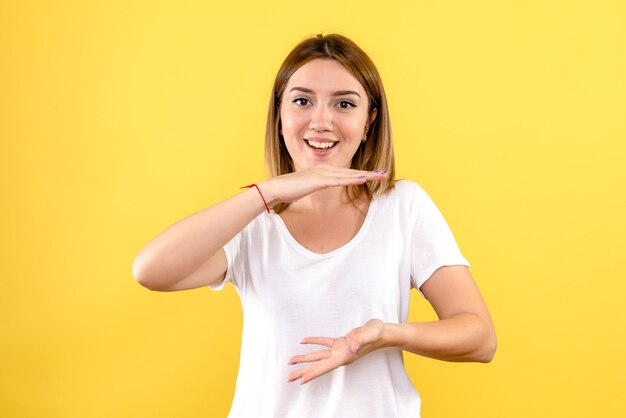 Vista frontale della giovane donna sorridente sulla parete gialla