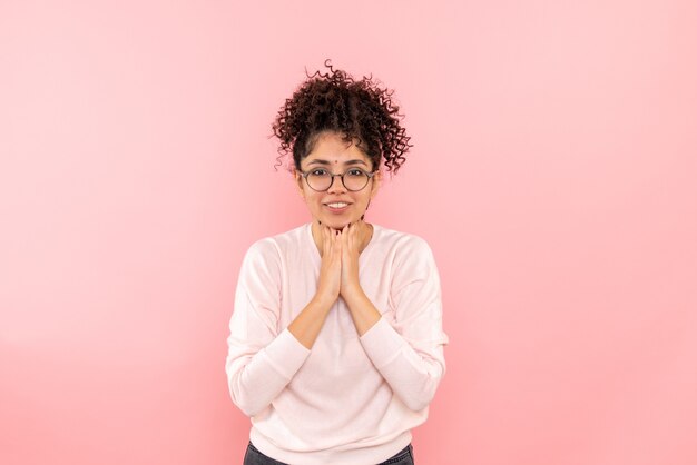 Vista frontale della giovane donna sorridente sulla parete rosa