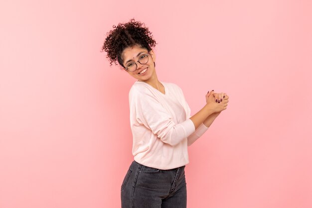 Vista frontale della giovane donna sorridente sulla parete rosa