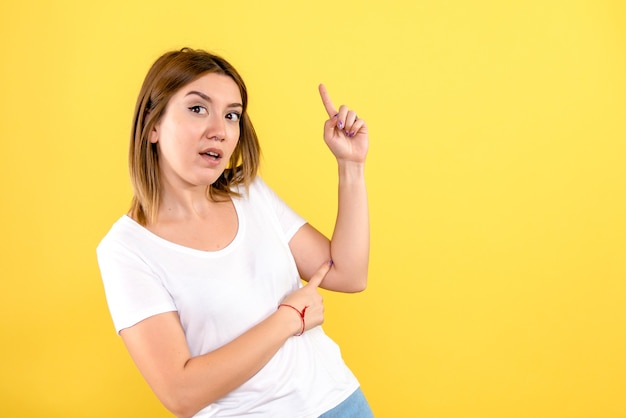 Vista frontale della giovane donna sulla parete gialla