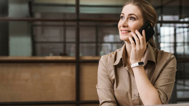 Vista frontale della giovane imprenditrice parlando al telefono durante una riunione