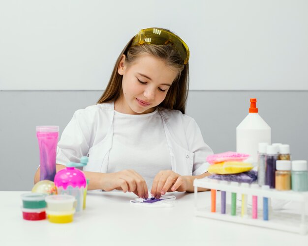 Vista frontale della giovane ragazza scienziato che produce melma