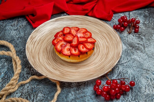 Vista frontale della gustosa torta di fragole con bacche rosse sulla superficie scura