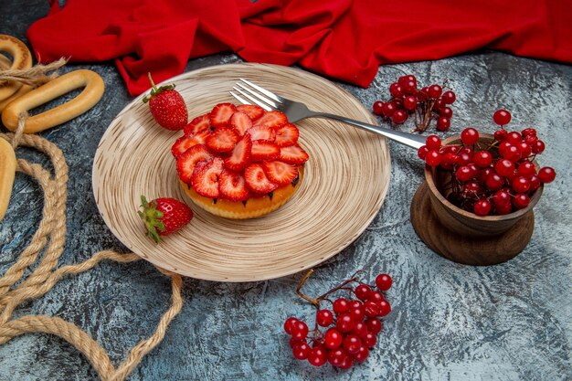 Vista frontale della gustosa torta di fragole con frutti di bosco sulla superficie scura