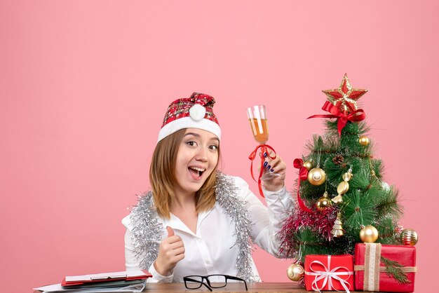 Vista frontale della lavoratrice che celebra il Natale con un bicchiere di champagne in rosa