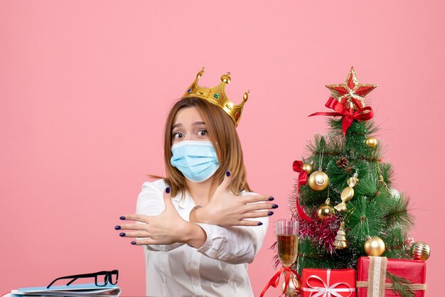 Vista frontale della lavoratrice in maschera sterile con corona stringe la mano sul rosa