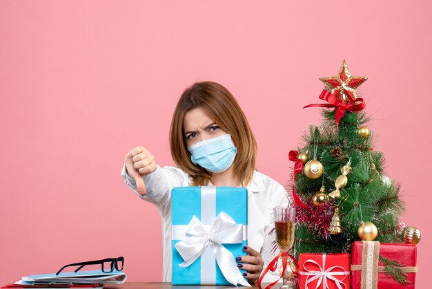 Vista frontale della lavoratrice in maschera sterile con regali in rosa