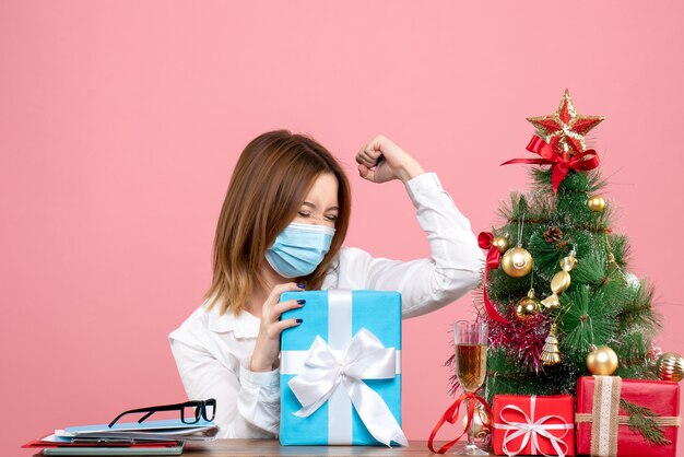 Vista frontale della lavoratrice in maschera sterile con regali in rosa