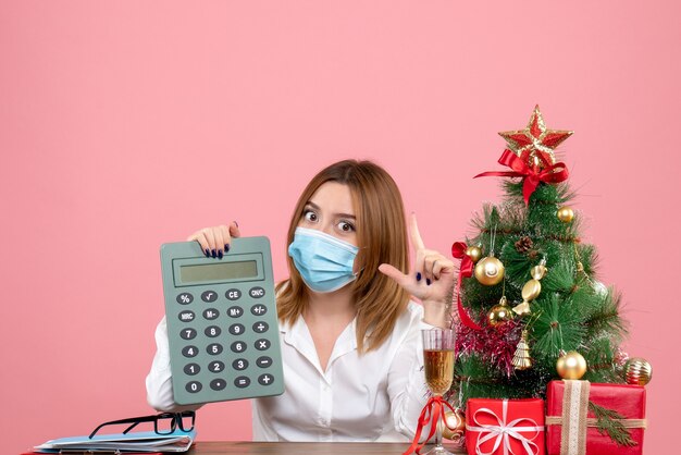 Vista frontale della lavoratrice in maschera sterile tenendo il calcolatore sul rosa