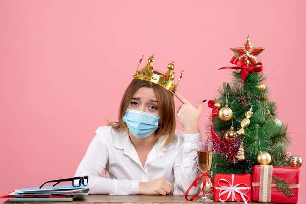 Vista frontale della lavoratrice seduta in maschera sterile con corona in rosa