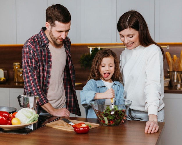 Vista frontale della madre e del padre con il bambino che prepara il cibo in cucina