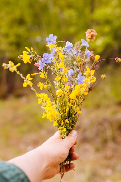 Vista frontale della mano che tiene il mazzo di fiori