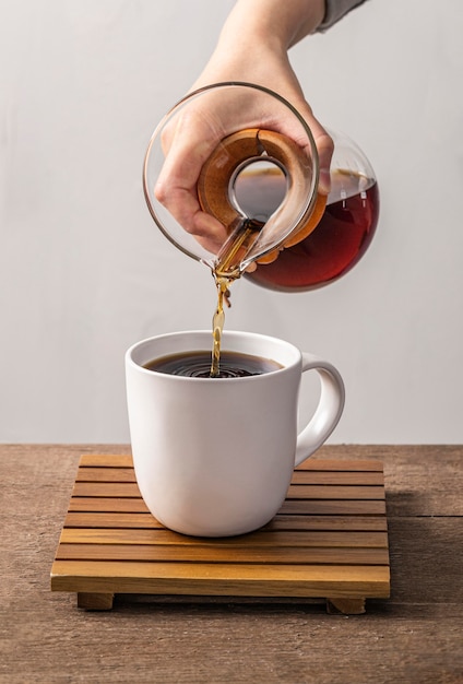 Vista frontale della mano che versa il caffè nella tazza