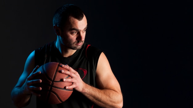 Vista frontale della palla della tenuta del giocatore di pallacanestro con lo spazio della copia