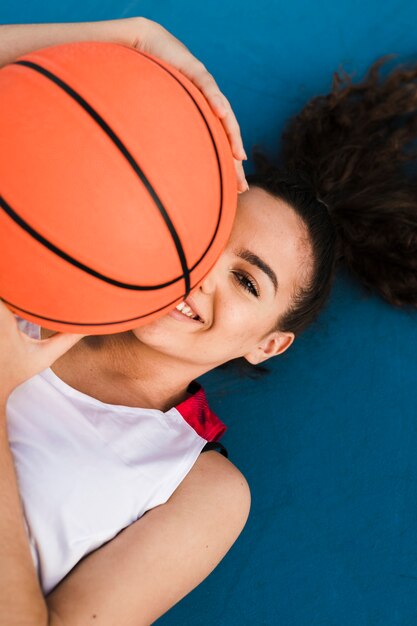 Vista frontale della palla di pallacanestro della tenuta della ragazza