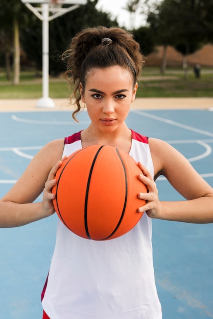 Vista frontale della palla di pallacanestro della tenuta della ragazza