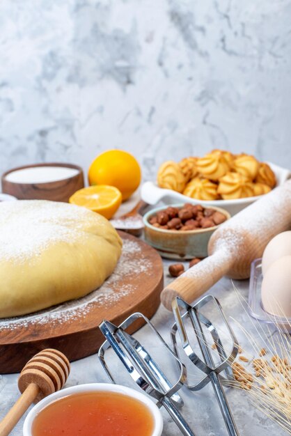 Vista frontale della pasta cruda su tavola rotonda di legno e set di vari alimenti grattugia su fondo di ghiaccio