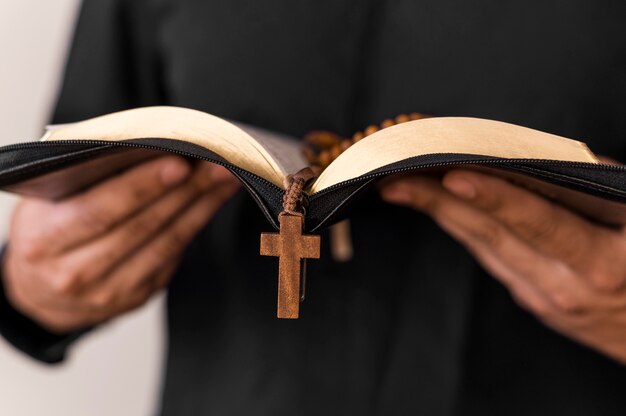 Vista frontale della persona con libro sacro e rosario