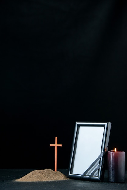 Vista frontale della piccola tomba con candela e cornice su nero