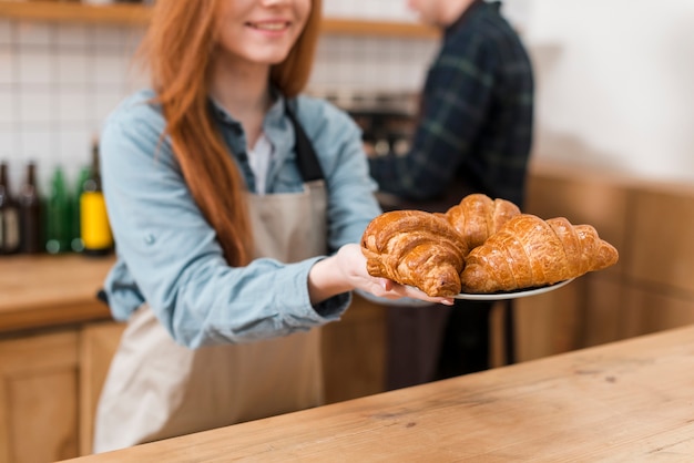 Vista frontale della ragazza barista con cornetti