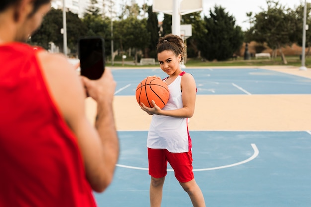 Vista frontale della ragazza che posa con la palla di baskeball